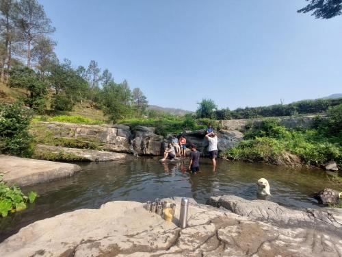 a group of people in a river with a dog at Kurmanchal Village by THE GHAUR in Almora