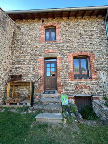 a brick house with a wooden door and stairs at Gite de l'Elevage de la Mûre in Saint-Just-Saint-Rambert