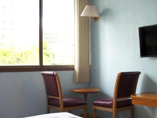 a room with two chairs and a table and a window at XX Wish Inn Chidlom BKK - วิช อินน์ ชิดลม in Makkasan