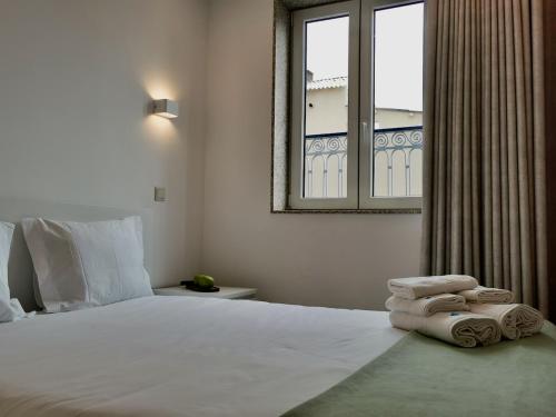 a bedroom with a large bed with towels on it at Cidade Alojamento in Póvoa de Varzim