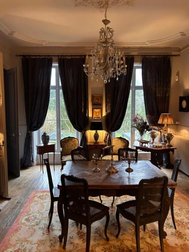 une salle à manger avec une table, des chaises et un lustre dans l'établissement Ardennes Manoir Blossom, à Vouziers