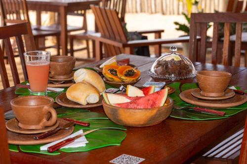 a table with bowls of fruit and a glass of juice at Amigos do Vento Chalés e Kite Point in Touros