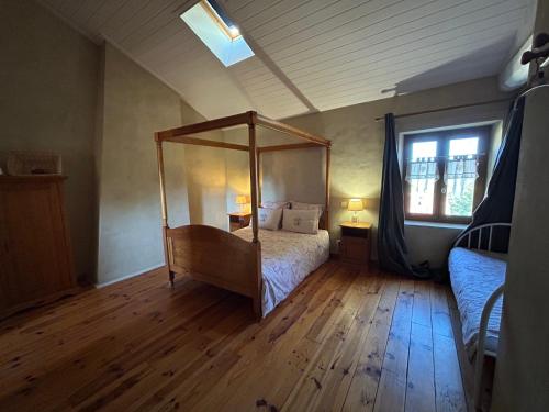 a bedroom with a canopy bed and a wooden floor at Gite de l'Elevage de la Mûre in Saint-Just-Saint-Rambert