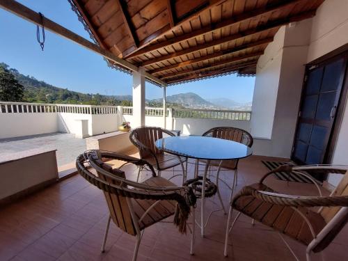 a patio with a table and chairs on a balcony at Alinda House Naukuchiatal by THE GHAUR in Bhīm Tāl