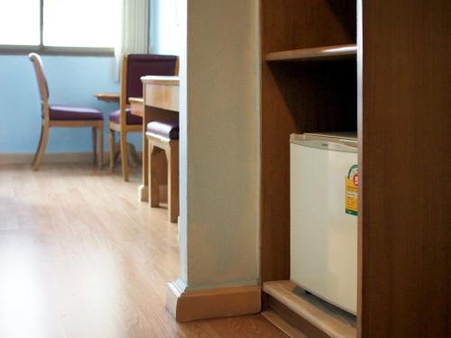 a room with a refrigerator and a table and chairs at XX Wish Inn Chidlom BKK - วิช อินน์ ชิดลม in Makkasan