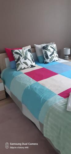 a bed with colorful blankets and pillows on it at Apartament Białystok in Białystok