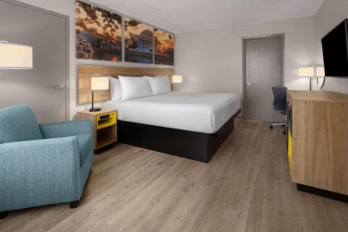 a hotel room with a bed and a chair at Days Inn of Frederick by Wyndham in Frederick