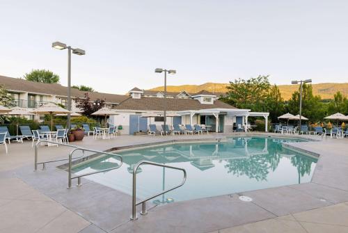 a large swimming pool with chairs and tables at Balcomo, a Ramada by Wyndham in Penticton