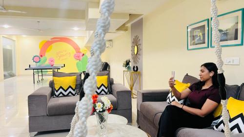 a woman sitting on a swing in a living room at BluO Studio5 Golf Course Road - Gym, Terrace Garden in Gurgaon
