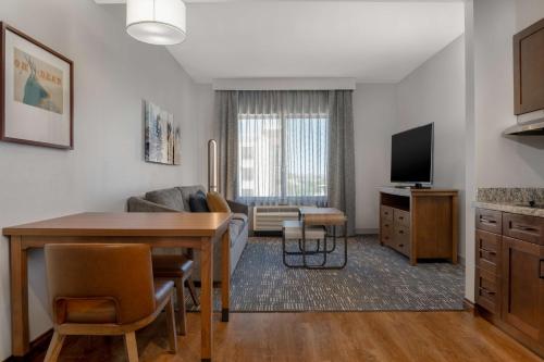 a living room with a table and a couch and a television at Homewood Suites by Hilton Billings in Billings