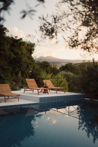 two chairs sitting next to a swimming pool at Palazzo Previtera Hotel & Restaurant in Linguaglossa