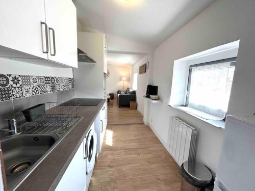 une cuisine avec des armoires blanches, un évier et une fenêtre dans l'établissement Hyper Centre Charmant T2 idéalement situé, à Vienne