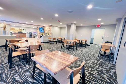 a cafeteria with wooden tables and chairs in it at AmericInn by Wyndham Glendale Milwaukee in Glendale