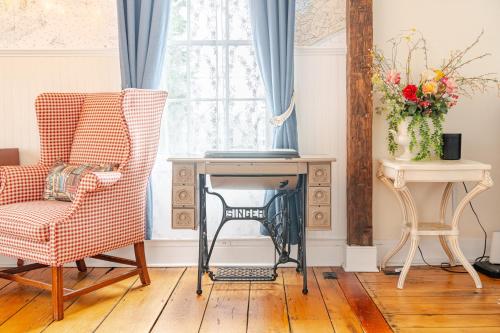 a living room with a chair and a table at Historic Seaside Captains House Downtown Mystic in Groton