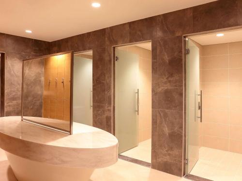 a bathroom with a walk in shower and a mirror at Novotel Jazan in Jazan