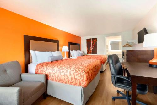 a hotel room with two beds and a desk at Howard Johnson by Wyndham Harrisonburg in Harrisonburg
