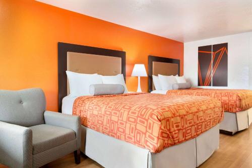 two beds in a room with an orange wall at Howard Johnson by Wyndham Harrisonburg in Harrisonburg
