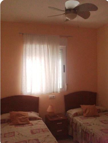 a bedroom with two beds and a window with a ceiling fan at Apartamento en Marina Trébol III, centro de Mágic World in Oropesa del Mar