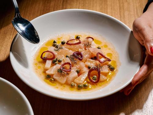 a person holding a white bowl of soup with seafood at Novotel Melbourne Airport in Melbourne