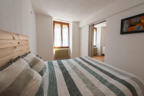 a bedroom with a bed with a striped comforter at Agréable maison de ville in Vincelles