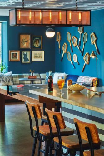 a bar in a restaurant with a counter with chairs at Graduate by Hilton Charlottesville in Charlottesville