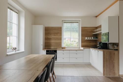 a kitchen with white cabinets and a wooden table at Chalupa Bezvětří in Malá Morávka