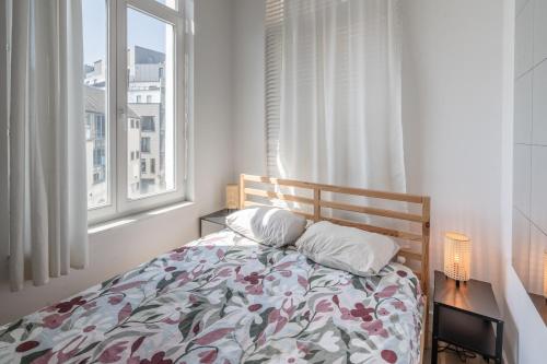 1 Schlafzimmer mit einem Bett mit einer Blumendecke und einem Fenster in der Unterkunft Light Modern Apartment in the Heart of Antwerp in Antwerpen