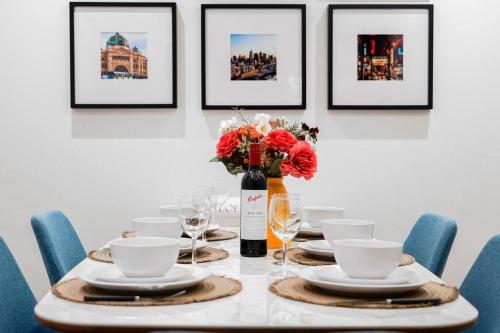 a table with plates and a vase with flowers on it at Highrise Skyline Spectacular View Luxury 2B2B1C in Box Hill