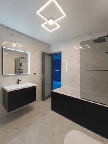 a bathroom with a sink and a tub and a mirror at Holiday House "M" Omiš - Newly renovated house with swimming pool, 3 rooms, gym, large terrace with amazing view on town and 6 parkplaces in Omiš