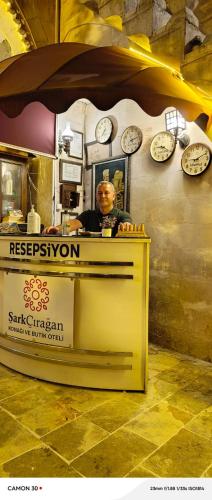 a man sitting behind a counter with clocks on the wall at Şark Çırağan Konak Boutique Hotel in Urfa