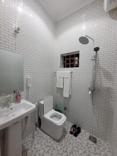 a white bathroom with a toilet and a sink at Jawda in Nungwi