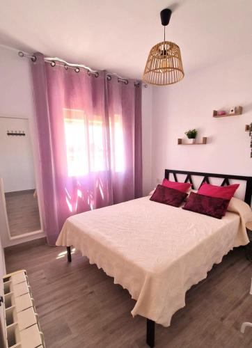 a bedroom with a large bed with red pillows at Apartamento turístico "Mi casina" AT-CC-00782 in Casar de Cáceres