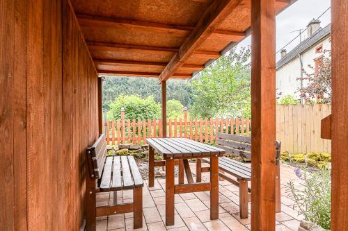 a porch with two benches and a table and a fence at Die Alte Metzgerei in Malberg