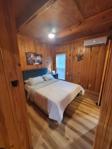a bedroom with a large white bed in a wooden room at 109 Vinewood Cabin-1 Bedroom in Brewton