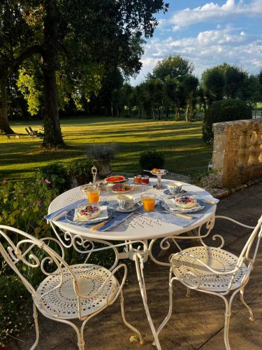 ein Tisch mit Tellern voller Essen und zwei Stühlen in der Unterkunft Le Bouquet Bleu Bed and Breakfast in Siorac-en-Périgord