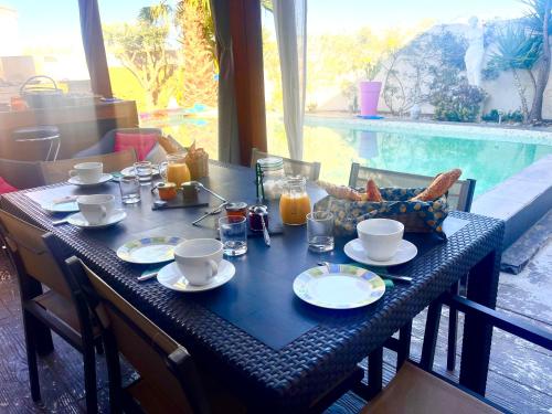 a table with breakfast food on it with a view of a pool at Villa Des Romieux in Pinet