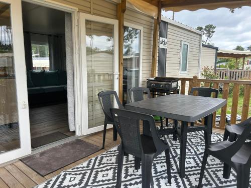 - une table et des chaises sur la terrasse couverte d'une maison dans l'établissement Camping Les Viviers chez So Claouey, à Lège-Cap-Ferret