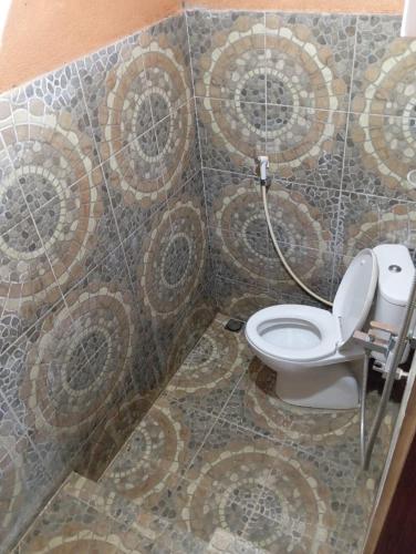 a bathroom with a toilet and a tile wall at Para para cafe & cottage in Berastagi
