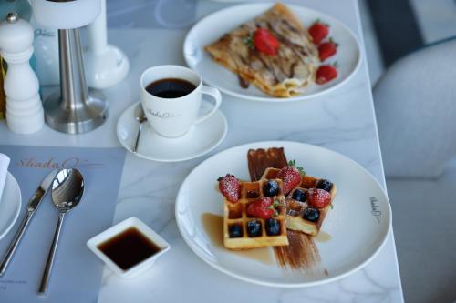a table with two plates of waffles and a cup of coffee at Shada Sea Hotel in Ḑubā