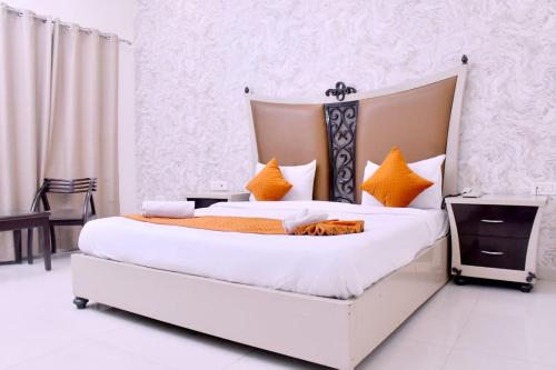 a bedroom with a large white bed with orange pillows at Nirmal Hotel And Resort in Bareilly