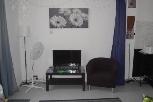 a living room with a chair and a table and a television at Dawlish Warren Welcome Family Holiday Park Villa Clover Welcome2Warren South Devon in Dawlish Warren