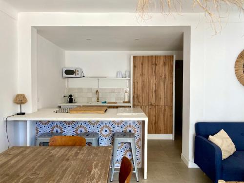 Il comprend une cuisine et un salon avec une table et un canapé bleu. dans l'établissement Rénové avec jardin à 5min de la plage, à Saintes-Maries-de-la-Mer