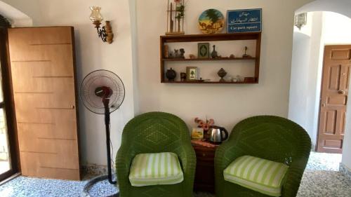 two green chairs in a room with a fan at فيلا في قريه الصحفيين in El Alamein