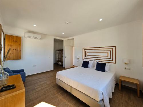 a bedroom with a white bed and a blue couch at Herdadinha in Vimieiro
