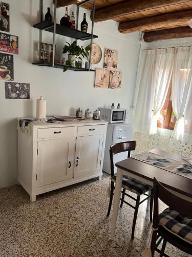 a kitchen with a table and a white cabinet at CASA NONNA ELISA Stayerat a SEGUSINO Valdobbiadene in Segusino