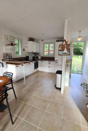 une cuisine avec des armoires blanches et un sol carrelé dans l'établissement Maison Confortable en forêt près des plages Aucun voisinage, à Saint-Pierre-dʼOléron