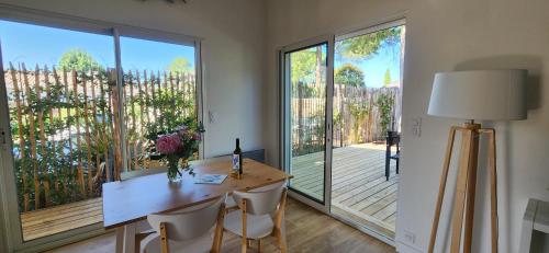 une pièce avec une table et des chaises et une grande fenêtre dans l'établissement LesOyats33 - Maisonnette avec accès Piscine, à Arès