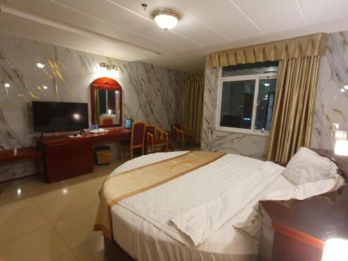 a bedroom with a bed and a desk and a television at Sea Light Hotel in Rach Gia
