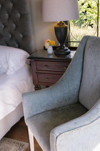 a bedroom with a bed and a chair next to a nightstand at Under Oaks Guesthouse in Paarl
