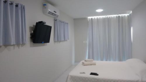 a white room with a bed and a tv at Pousada Brisa dos Ventos in São Miguel do Gostoso